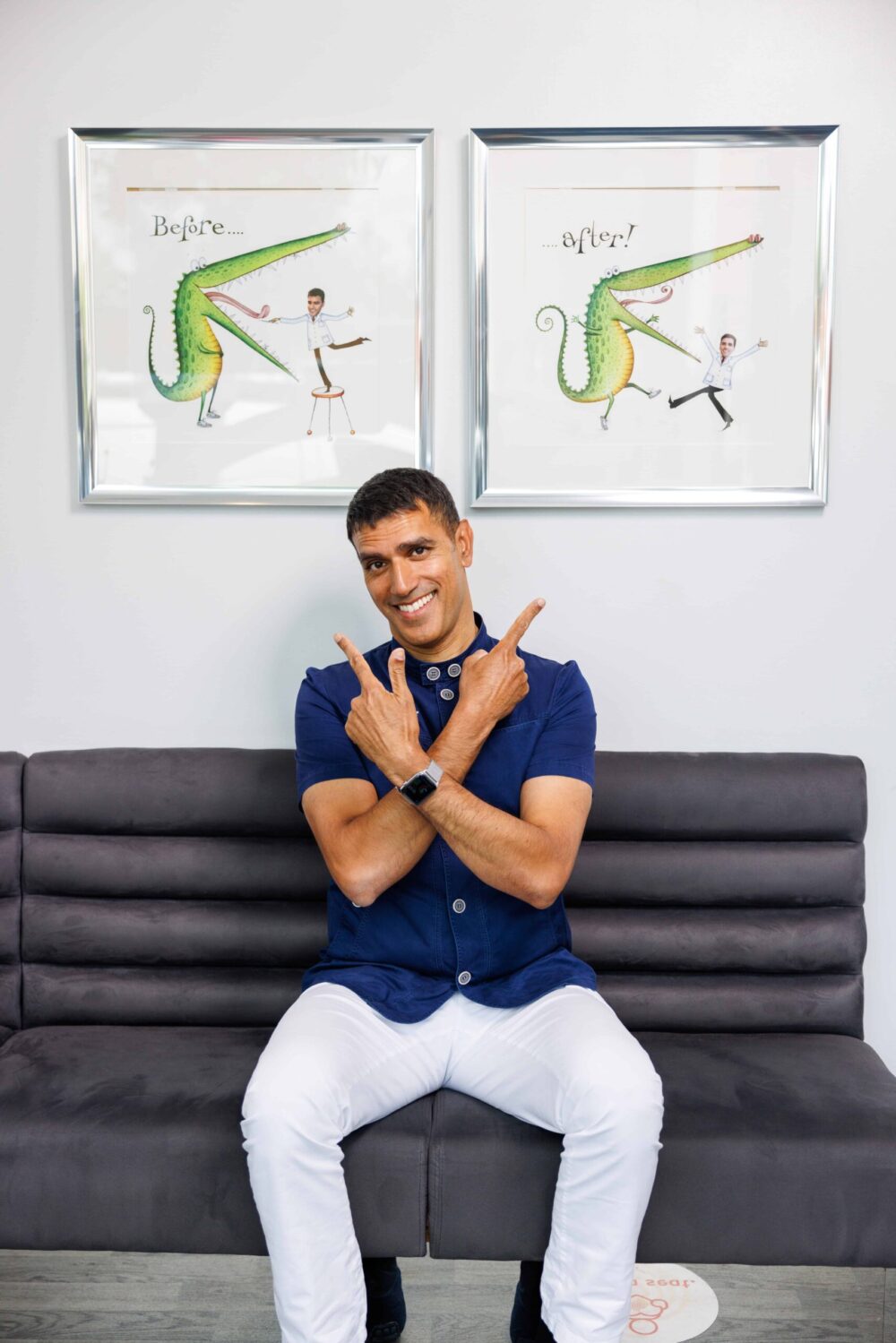 Dr Patel sitting on seating are in clinic pointing at framed art